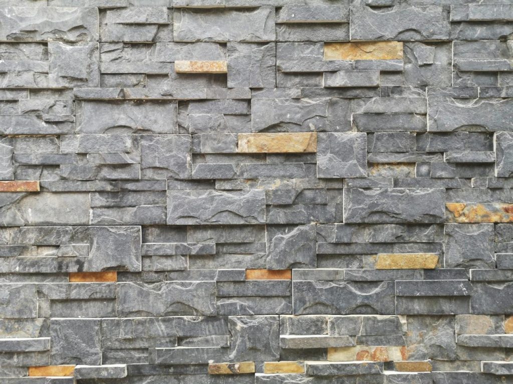 Gros plan d'un mur de pierre texturé fait de briques d'ardoise et de granit pour la conception architecturale.