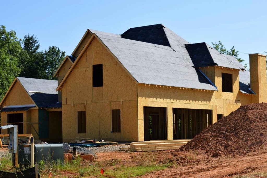 Une maison en bois partiellement construite en construction, présentant ses progrès et sa conception à la lumière du jour.
